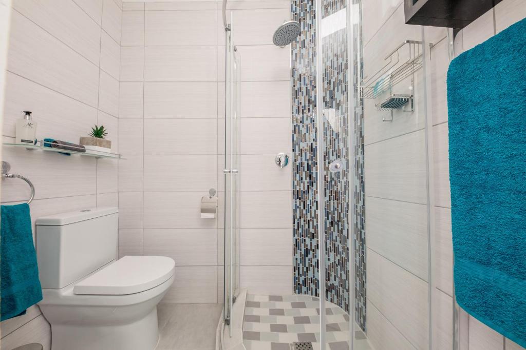 a bathroom with a toilet and a glass shower at Big Blue Accommodation in Bloubergstrand