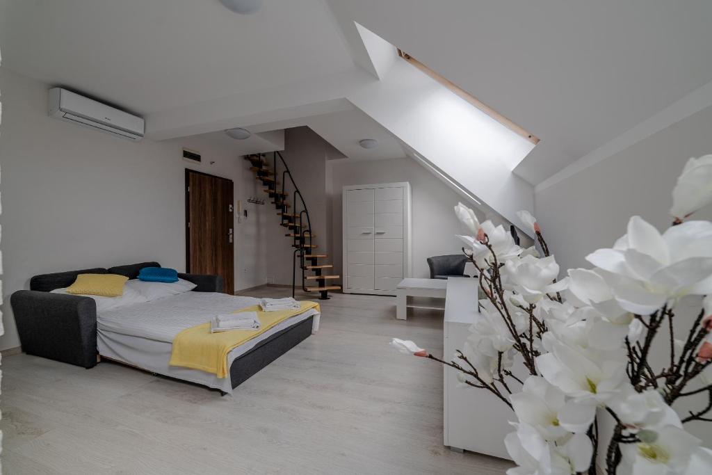 a white bedroom with a bed and a staircase at GUZ Apartamenty in Giżycko