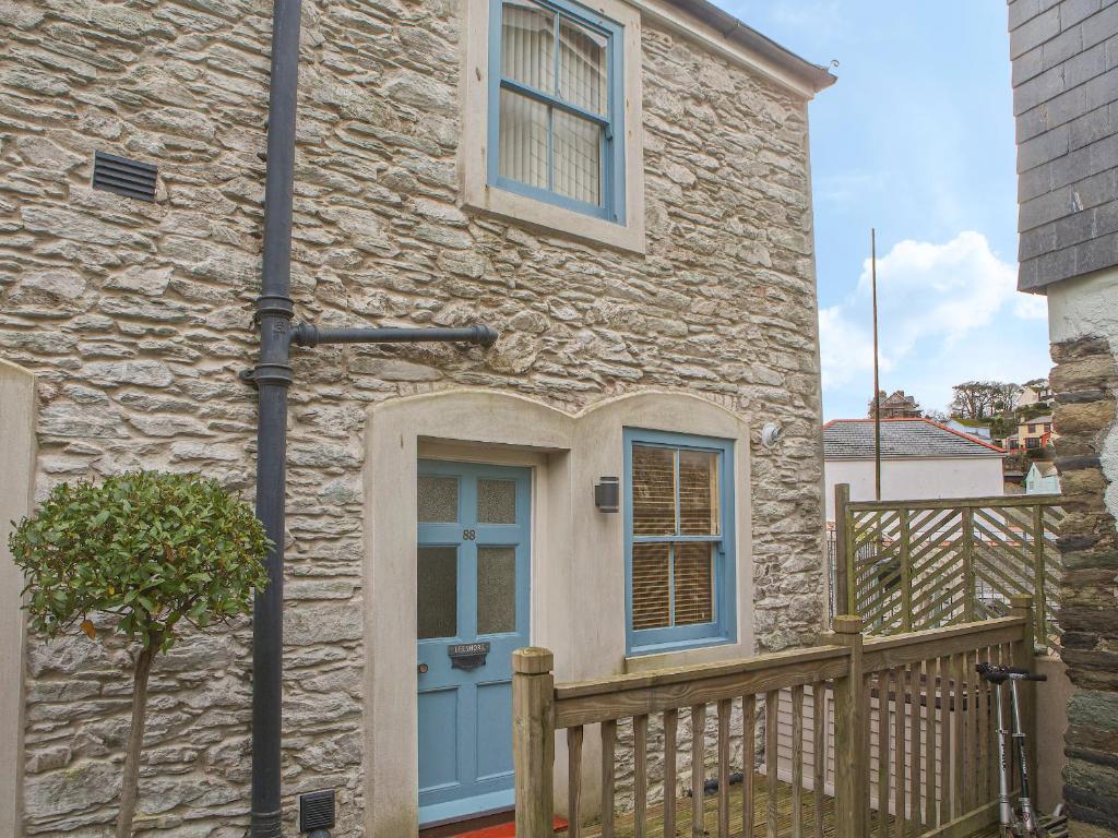a stone house with a blue door and a fence at Lee Shore in Salcombe