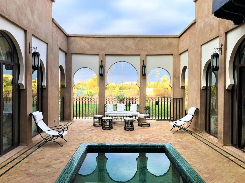 une terrasse avec une piscine, des chaises et une table dans l'établissement Villa Mayrit, Villa estilo Riad en un entorno único, à Marrakech