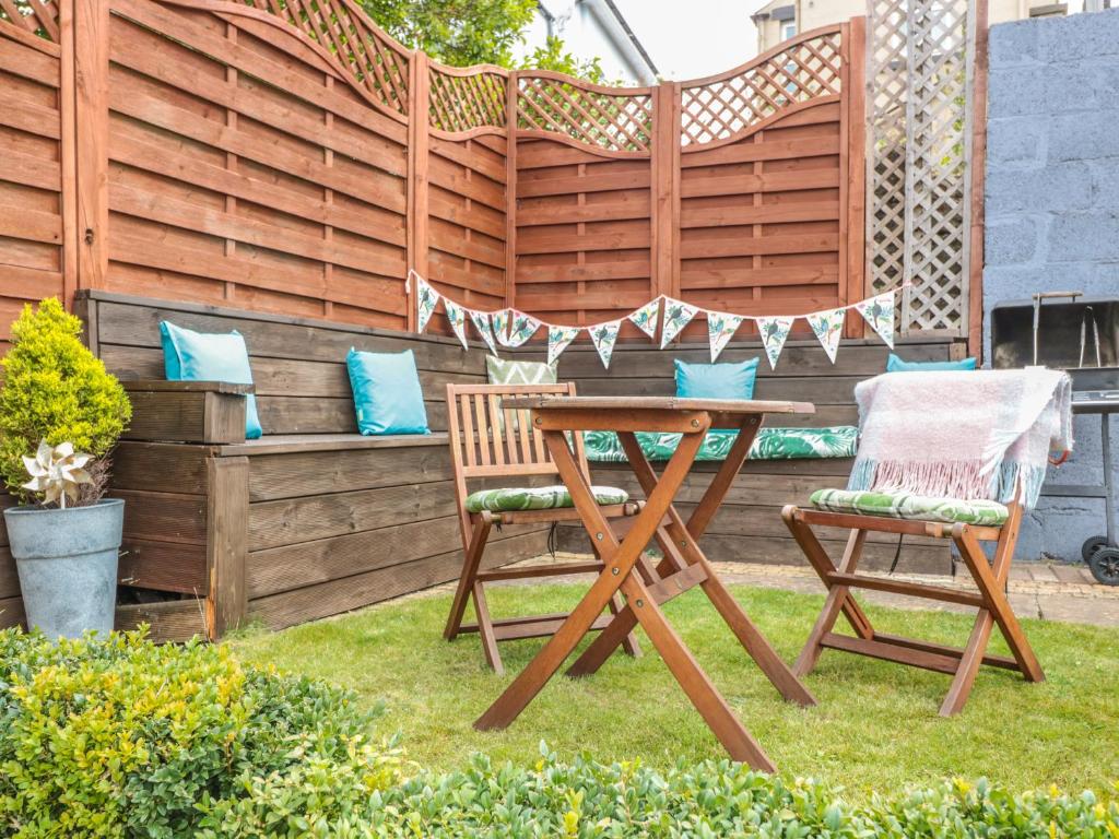 einen Tisch und zwei Stühle in einem Garten mit einem Zaun in der Unterkunft Church Road Annexe in Cinderford