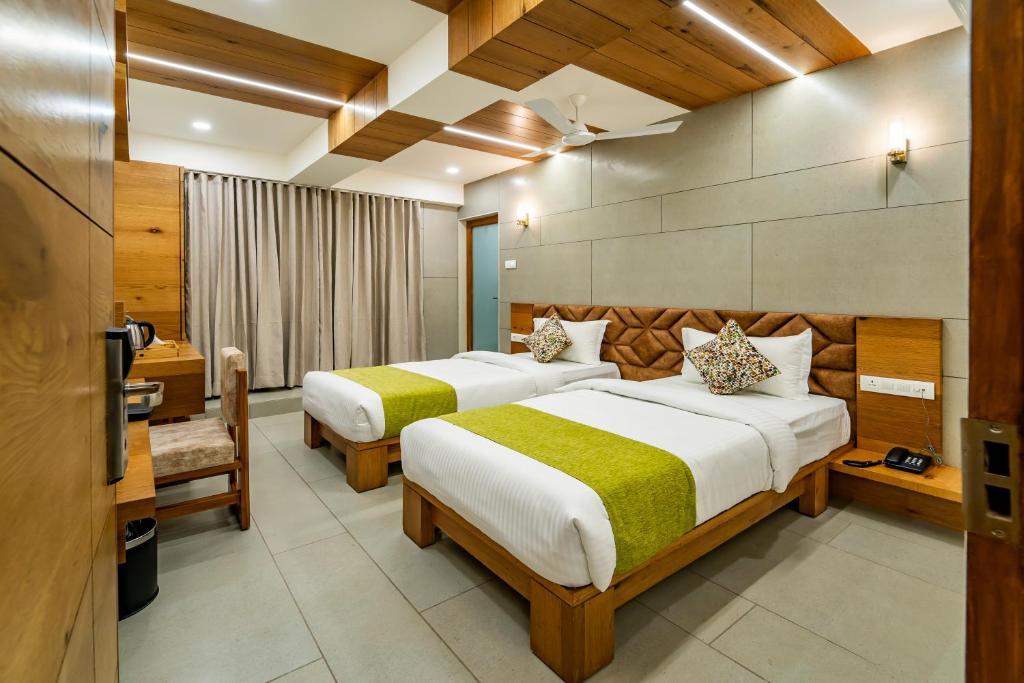 a hotel room with two beds and a desk at Hotel Pleasant Lake in Ahmedabad