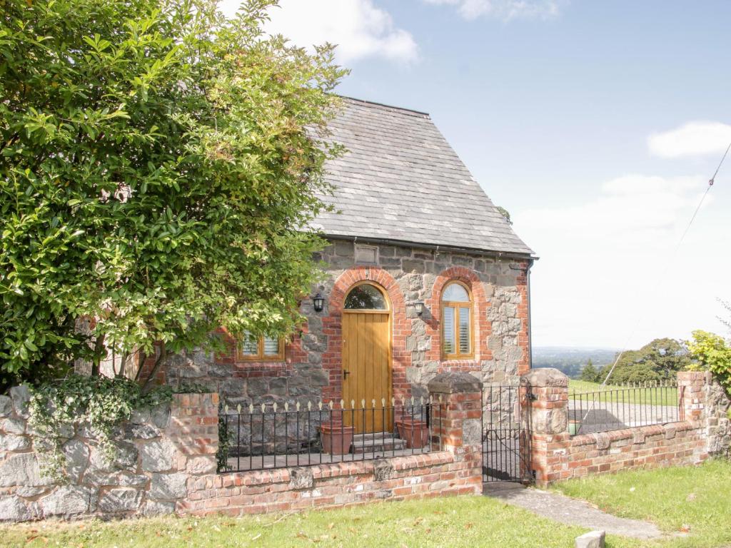 an old brick house with a yellow door at Bausley Chapel in Melverley