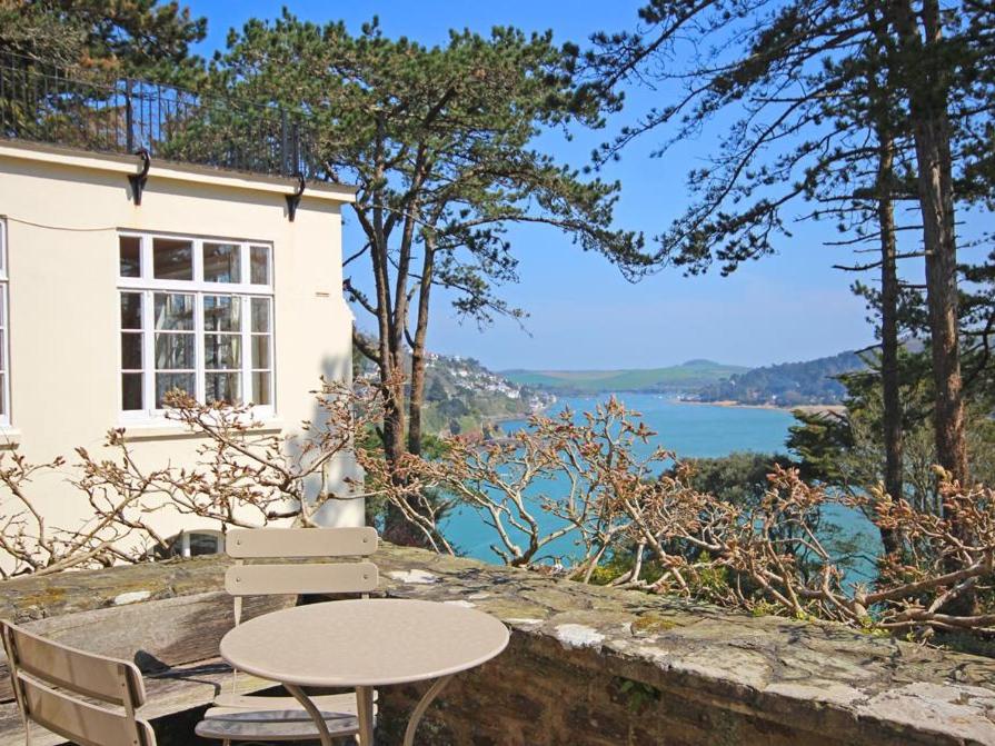 a table and chairs in front of a house overlooking the water at 4 Ringrone in Salcombe