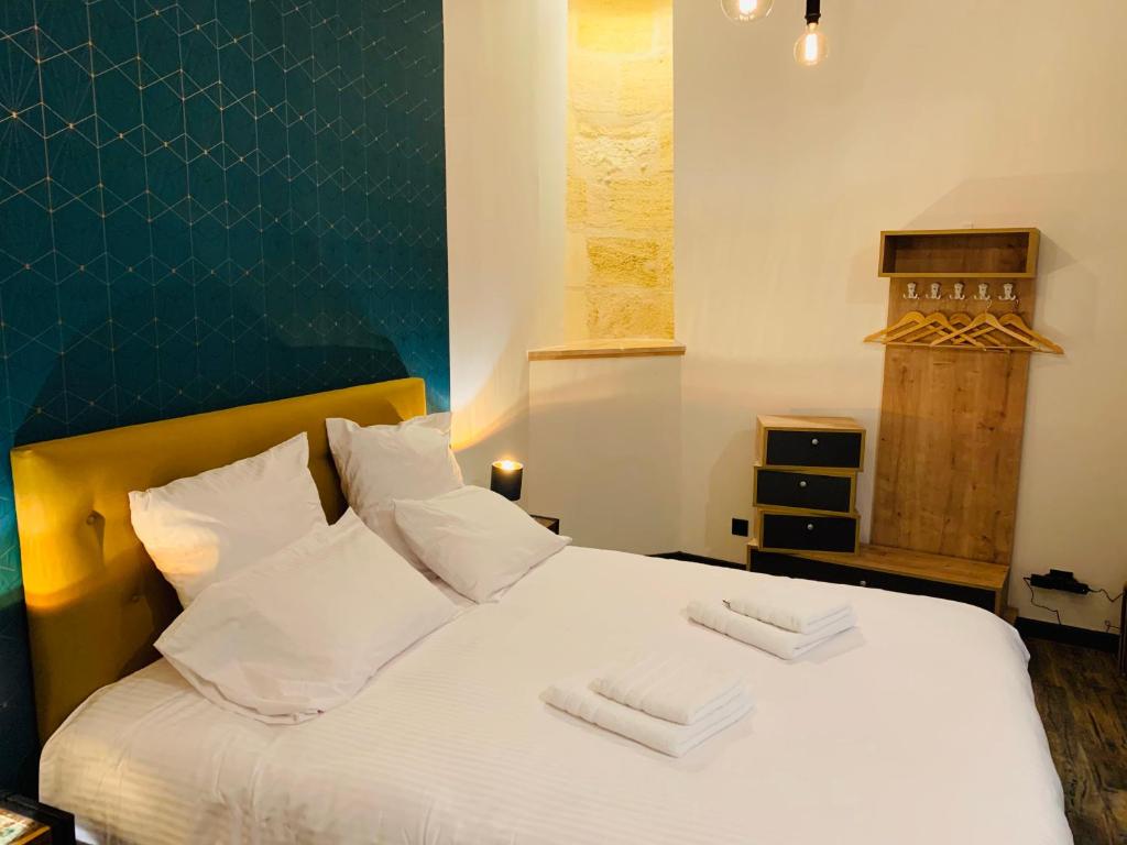 une chambre avec un lit blanc avec deux serviettes dessus dans l'établissement L’Atelier d’Hugla, à Bordeaux