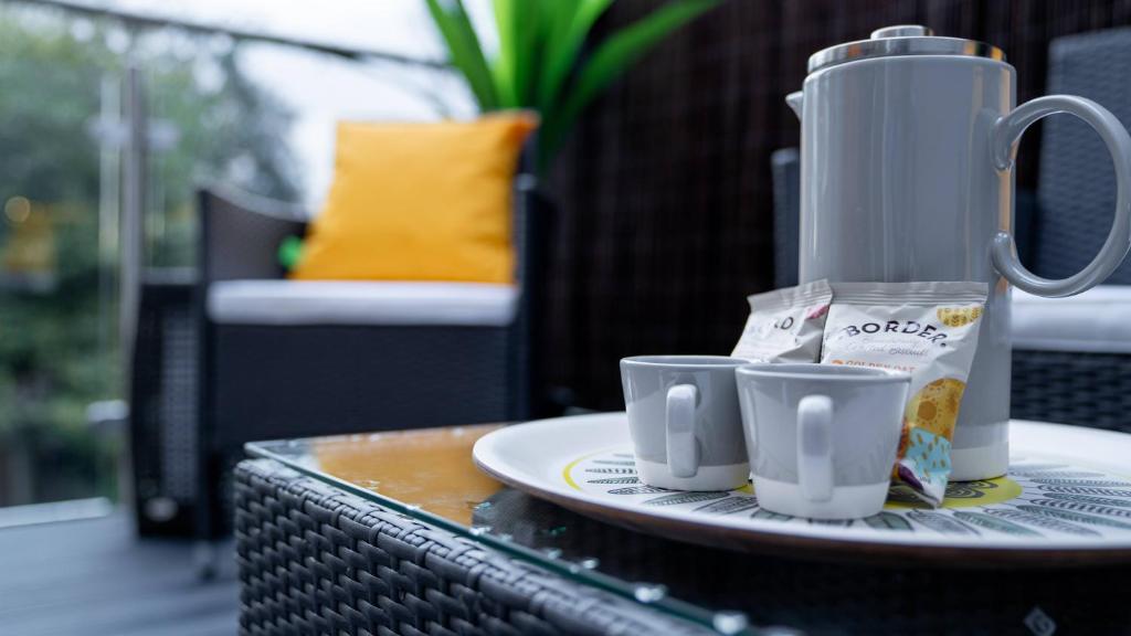 a table with a coffee maker and two cups on it at The Duplex Margate with Deck & Living Space Air Conditioning in Margate