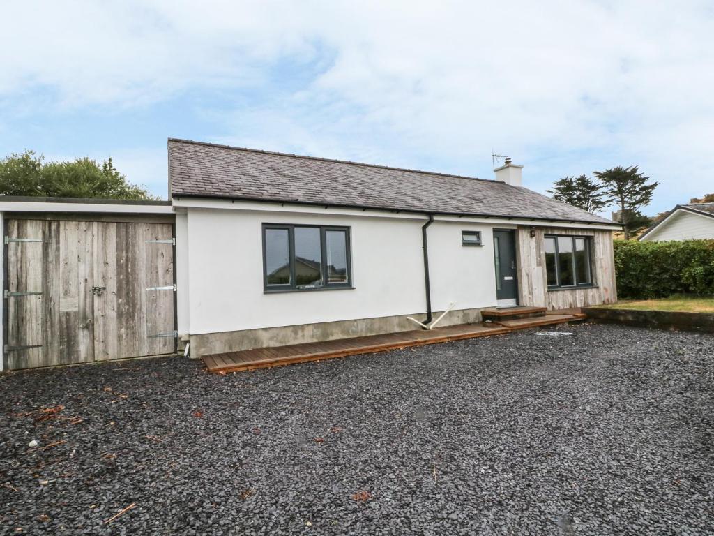 a white house with a fence and a driveway at Doldeg in Criccieth