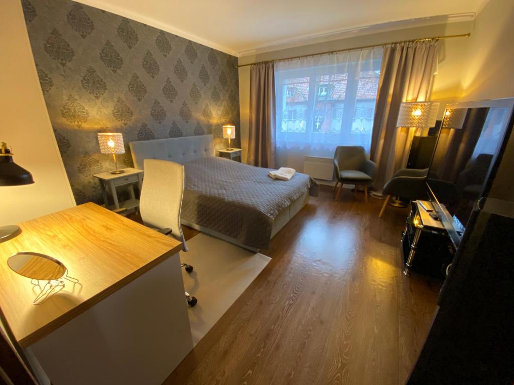 a hotel room with a bed and a desk and a room at DK Apartament Reymonta in Olsztyn