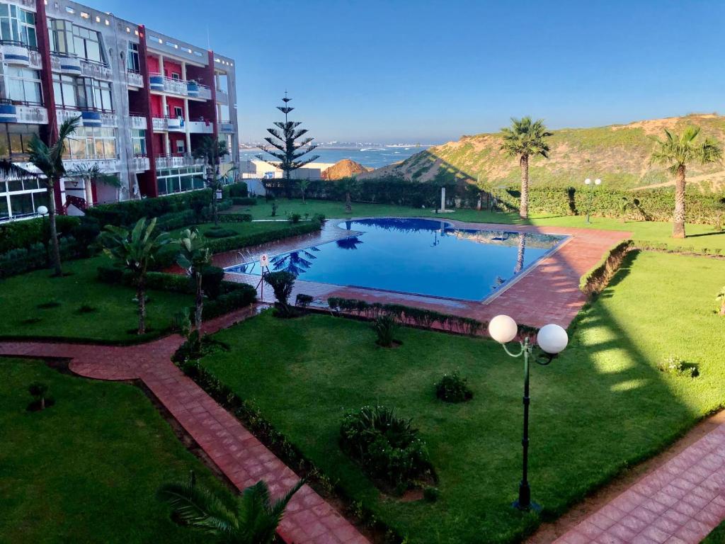 uma grande piscina num parque ao lado de um edifício em La Siesta Bel appartement bord de mer avec piscine em Mohammedia