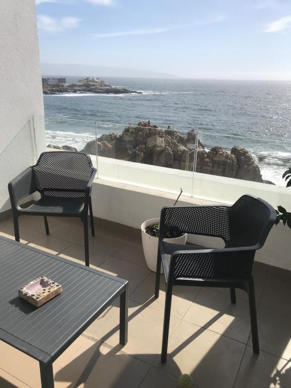 two chairs and a table on a balcony with the ocean at Departamento Terrazas de Cochoa 2 dormitorios in Viña del Mar