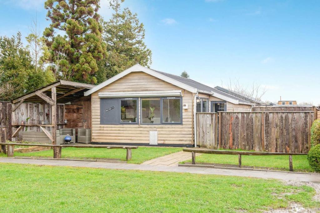 a home with a fence and a wooden house at Tinyhouse Dirkshorn Noord-Holland honden welkom omheinde tuin 10 km van strand in Dirkshorn
