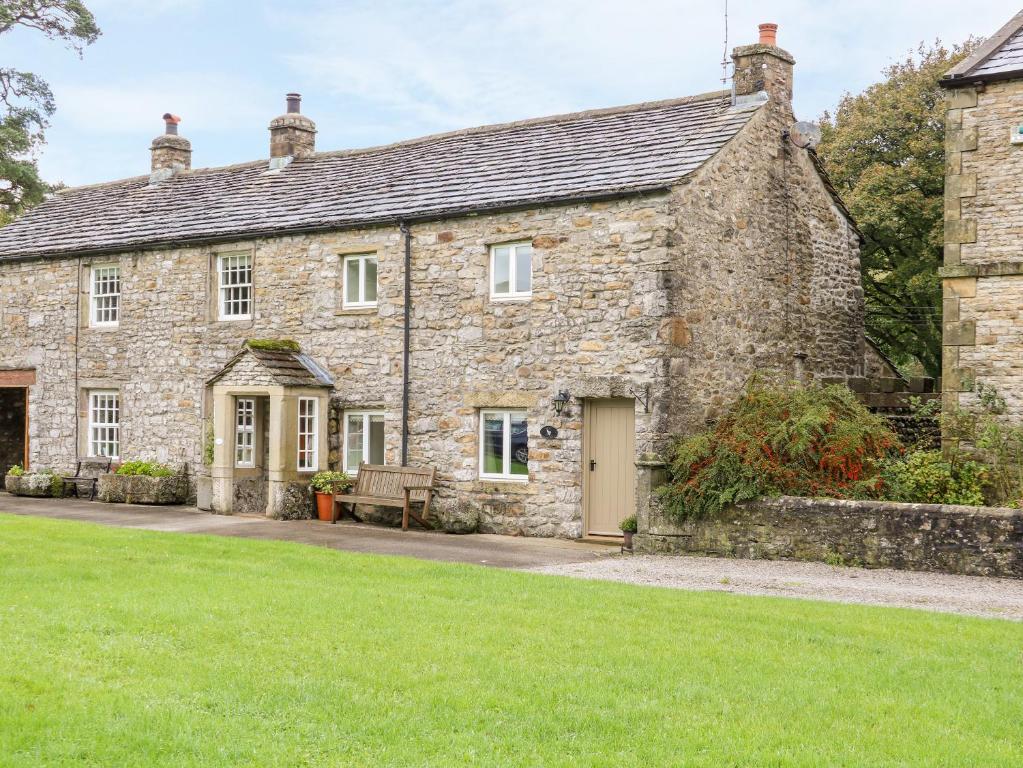 una antigua casa de piedra con césped verde en Croft Cottage en Skipton