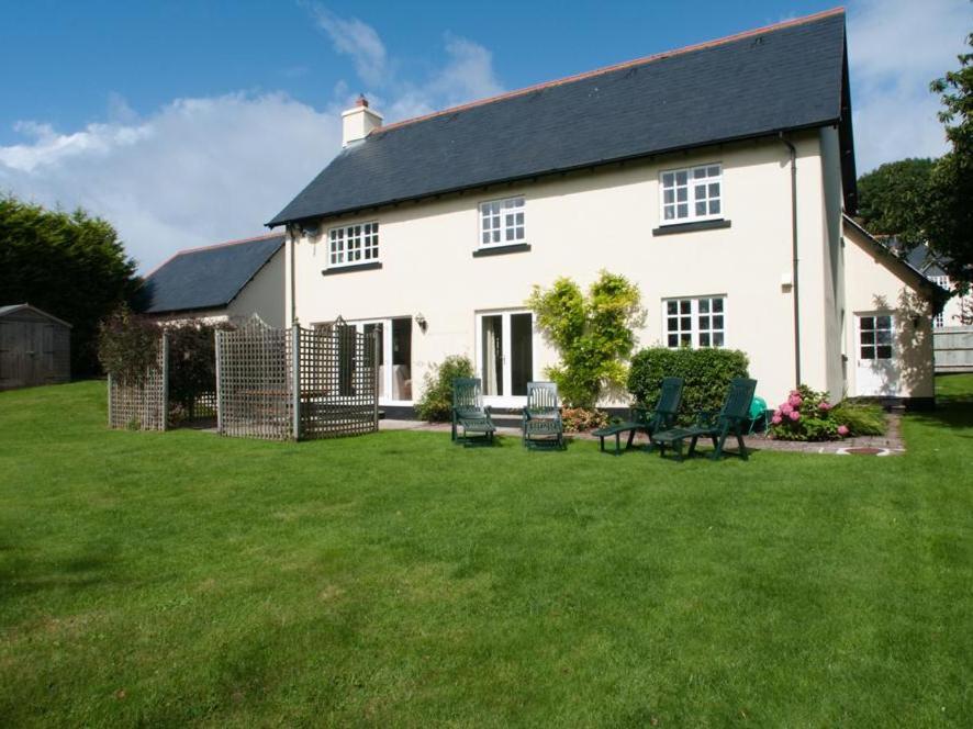 uma casa branca com um quintal com relva verde em Homefield House em Thurlestone