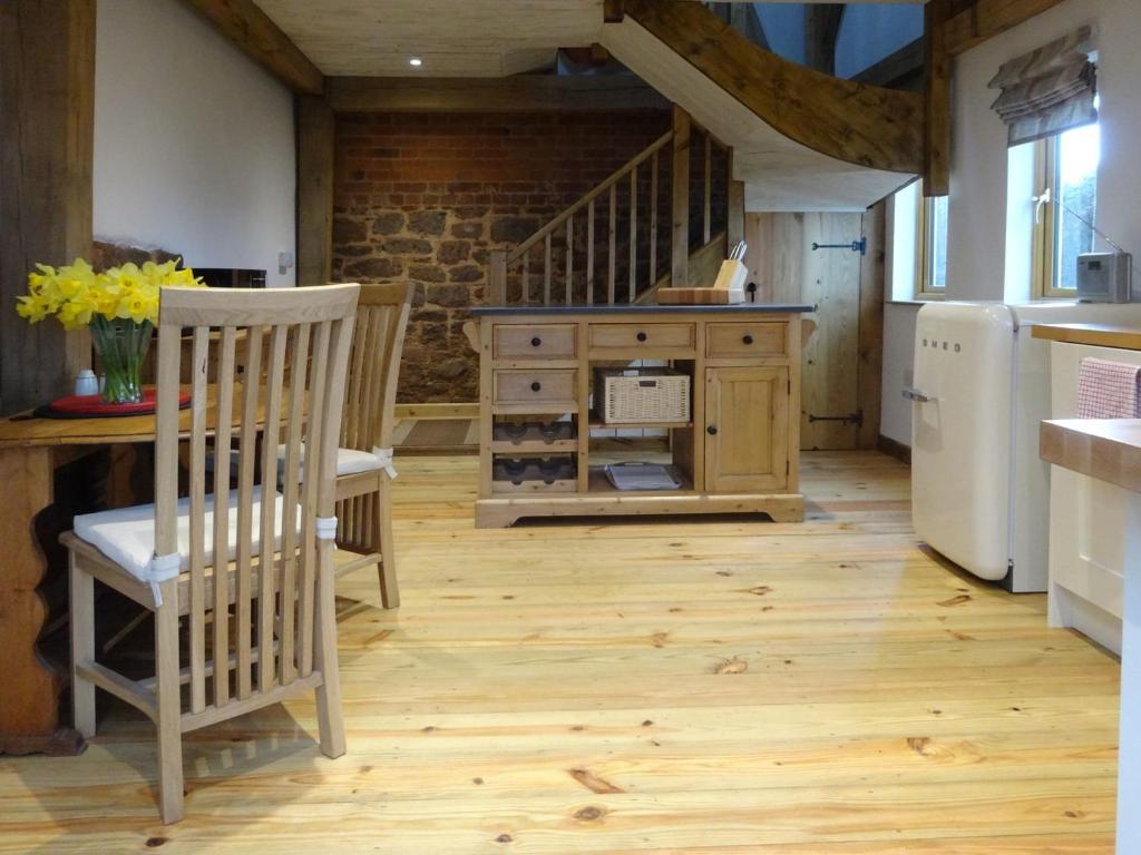 uma cozinha com pisos em madeira, uma mesa e cadeiras em The Woodshed em Upton Pyne