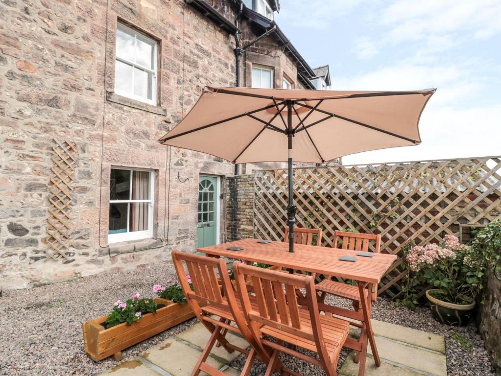 a wooden table with an umbrella in front of a building at 31 Peth Head in Wooler