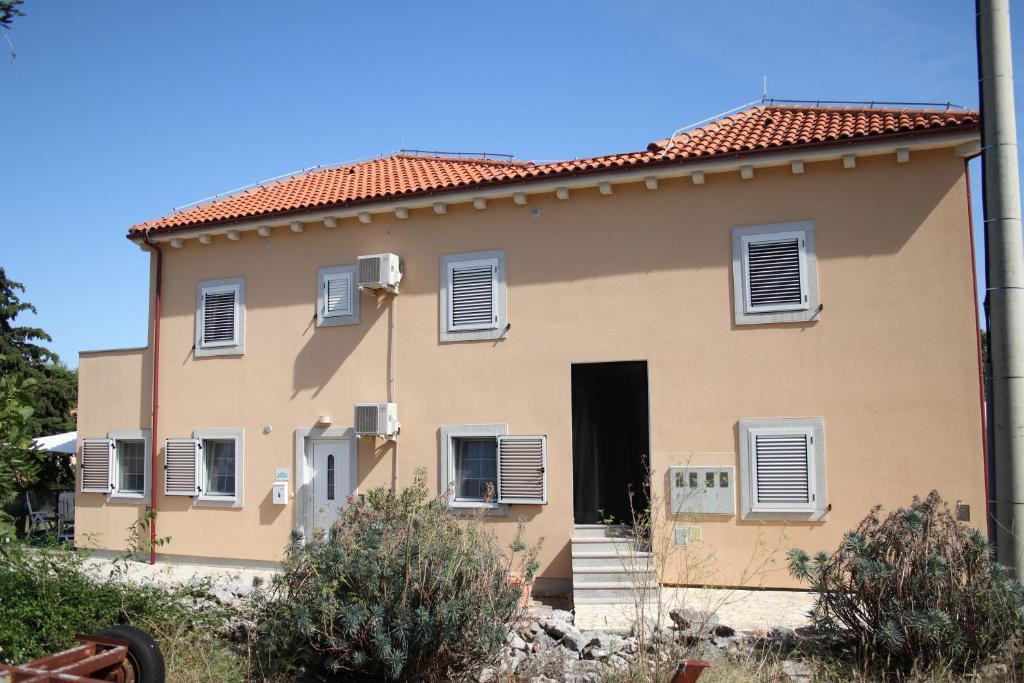a large tan house with a black door at Apartments Pegla in Nerezine