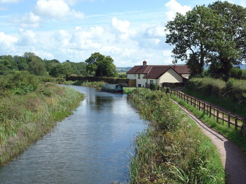 Ein Fluss mit einem Haus und einem Boot. in der Unterkunft Valley House in Tiverton