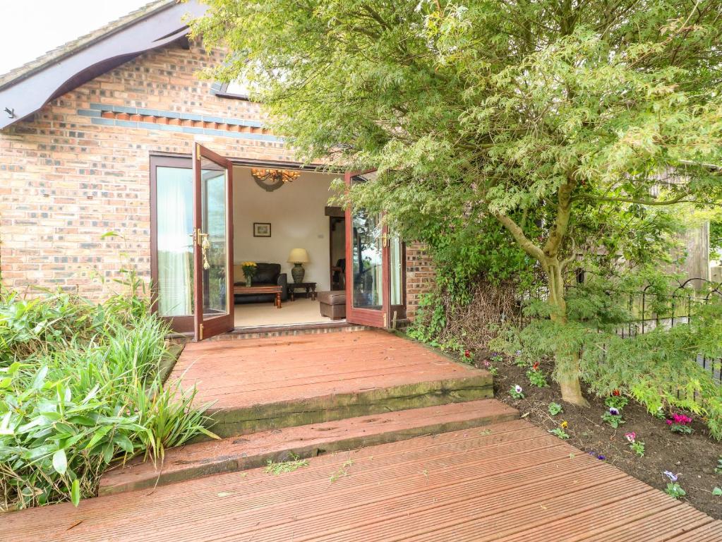 a wooden walkway leading to a brick house at Frog Meadow Barn in Biddulph