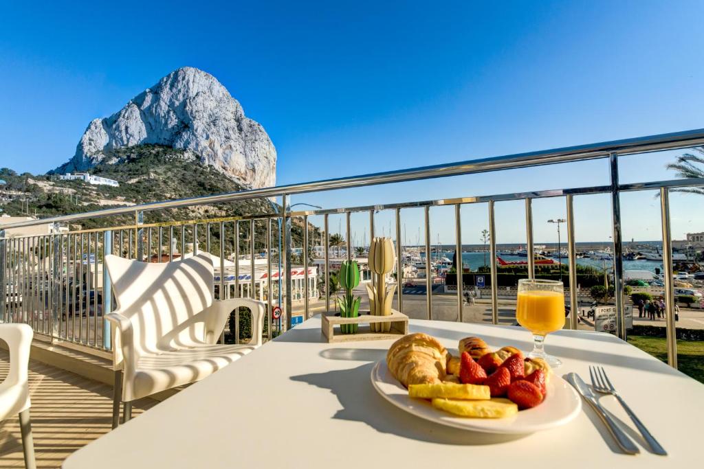 a table with a plate of food and a glass of orange juice at Hotel Porto Calpe in Calpe