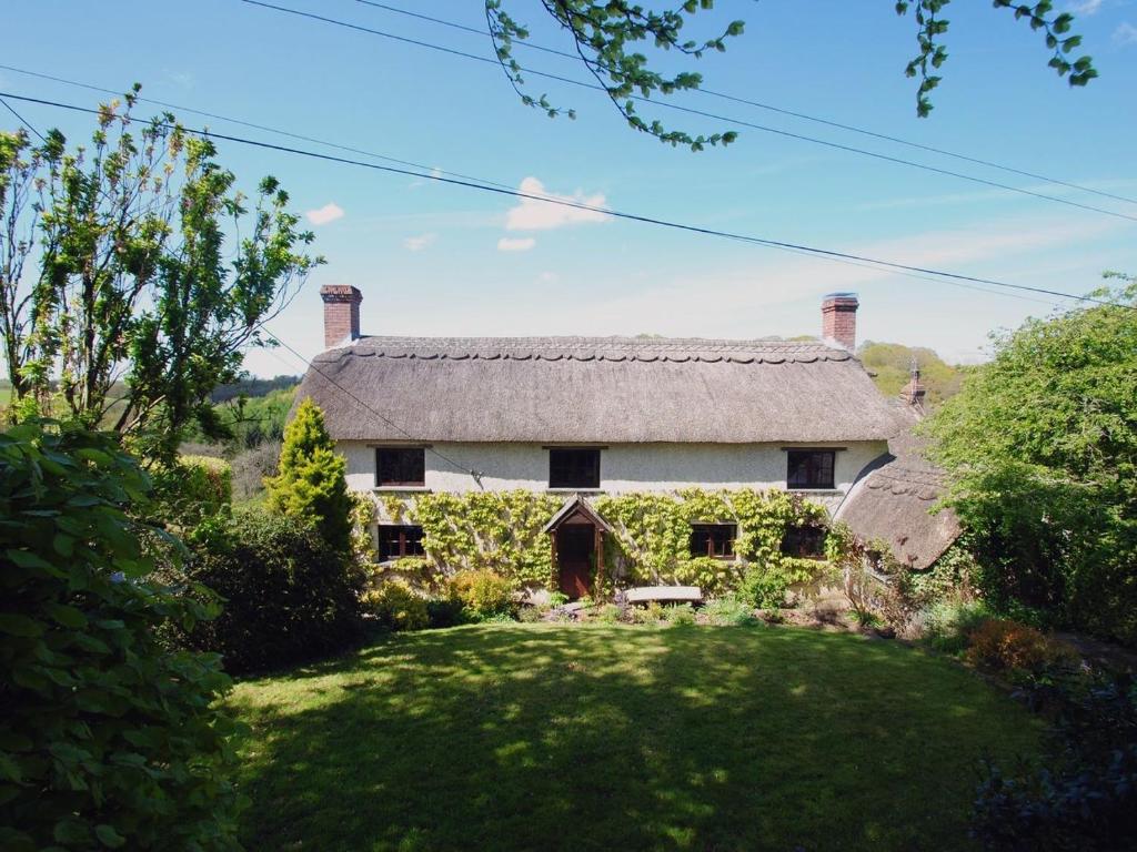 an old stone house with a thatched roof at Hope Cottage in Ashreigney