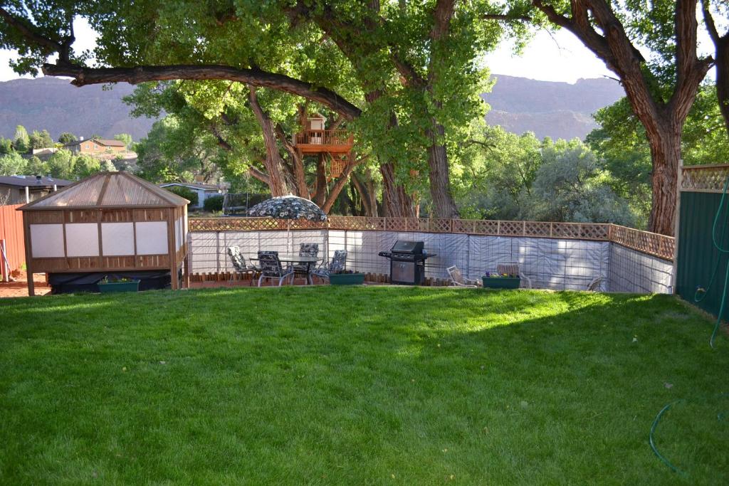 a yard with a fence and a tree with a house at Rustic Retreat Moab Townhome with Grill and Fire Pit! in Moab