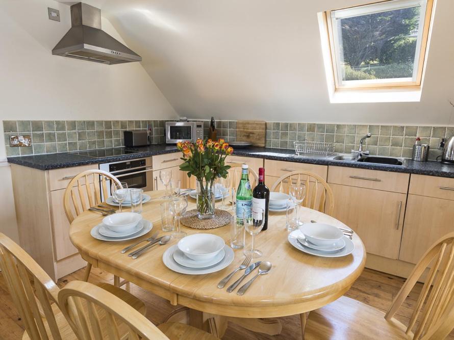 a kitchen with a wooden table with plates and wine glasses at 4 Armada House in Hope Cove