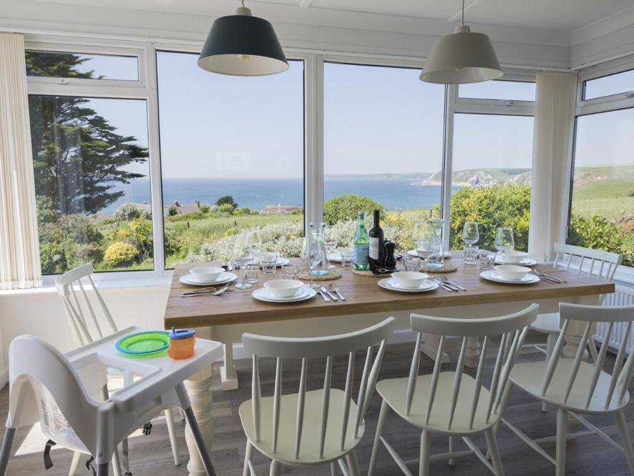 a dining room with a table and chairs and the ocean at Seaspray Bigbury-on-Sea in Bigbury on Sea