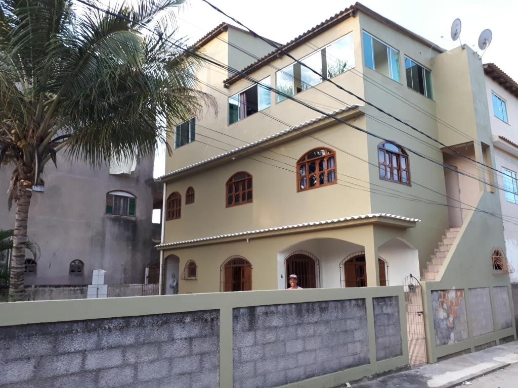 a house with a wall and a palm tree at Bourguignon in Piúma