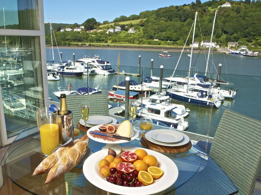 a table with plates of food on a table with boats at 7 Dart Marina in Dartmouth