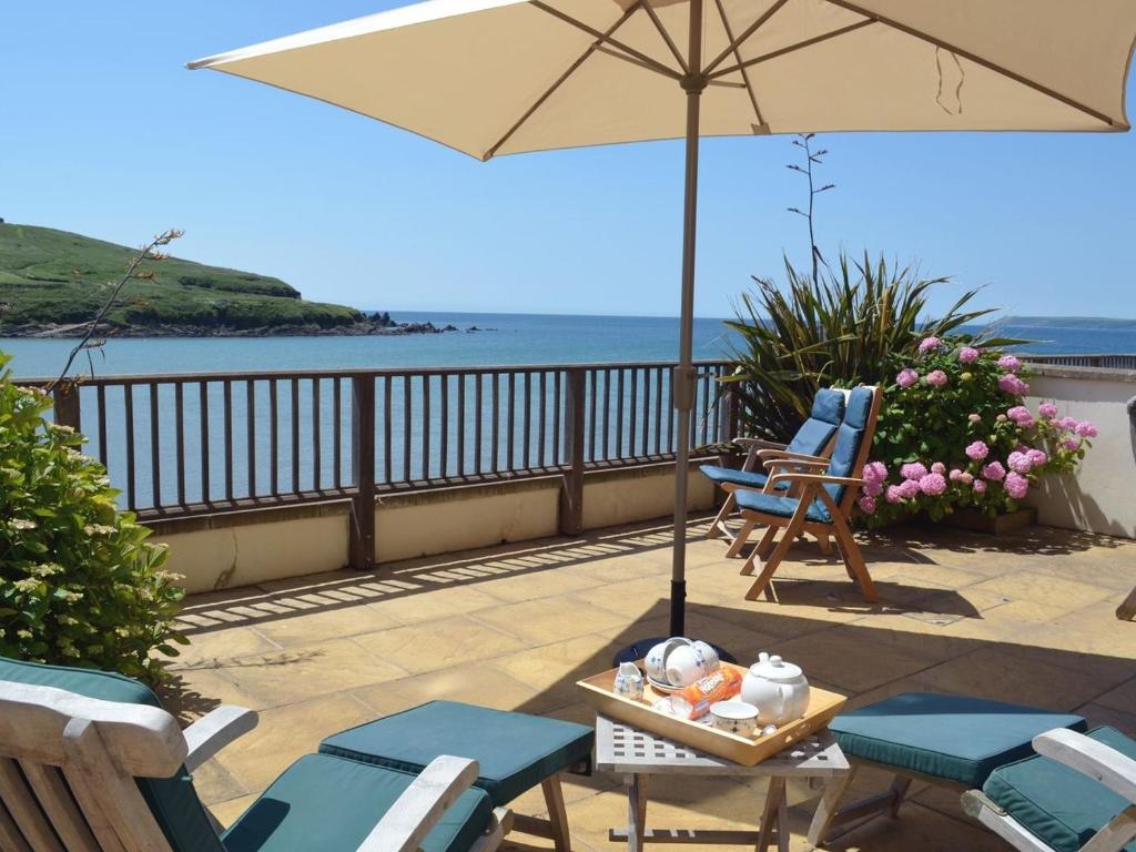 a patio with chairs and a table with an umbrella at 6 Burgh Island Causeway in Bigbury on Sea