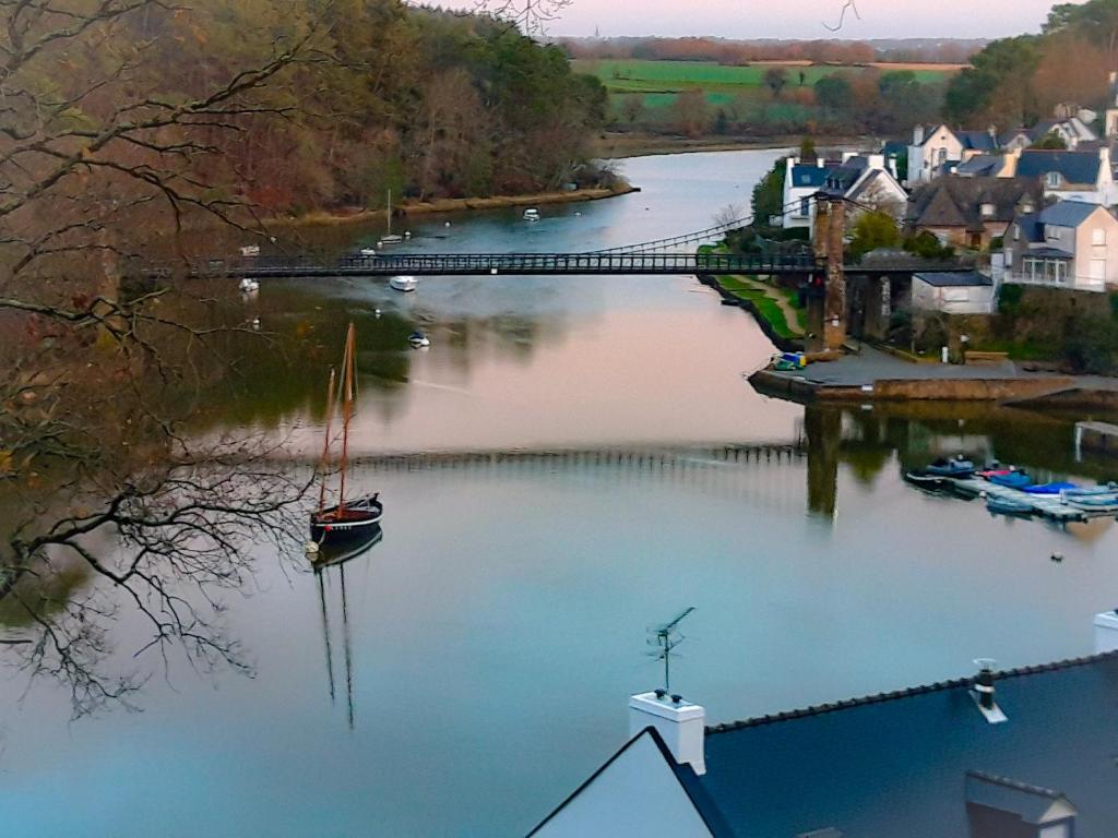 a river with a bridge and a boat in the water at Hotel Alicia Auray Le Bono in Le Bono