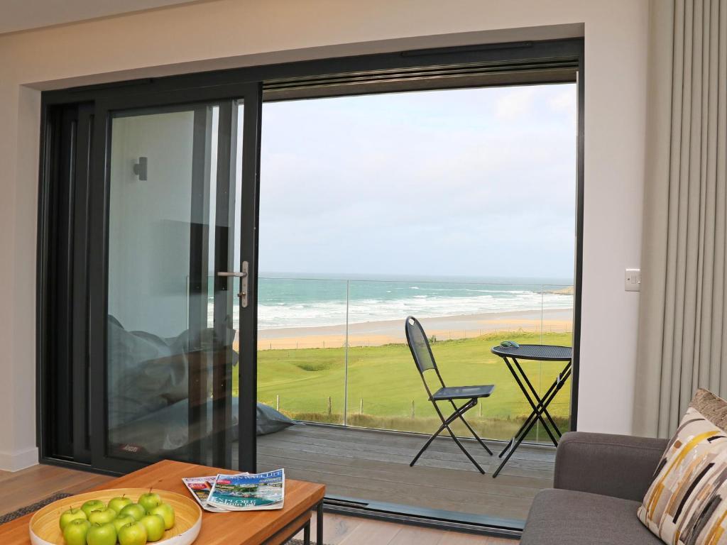 a living room with a sliding glass door with a view of the ocean at Little Fistral in Newquay