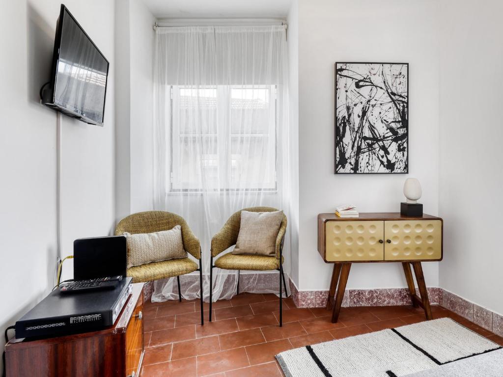 een woonkamer met een televisie en 2 stoelen bij Lisbon Graça Terrace in Lissabon
