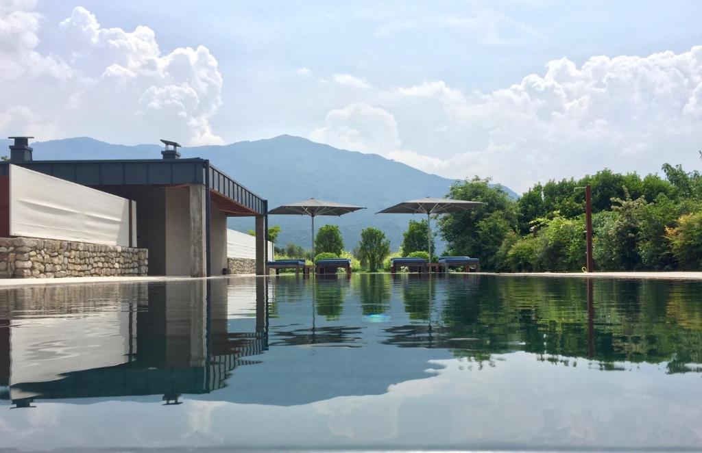 una piscina de agua con un edificio y montañas al fondo en Vivere Suites & Rooms, en Arco