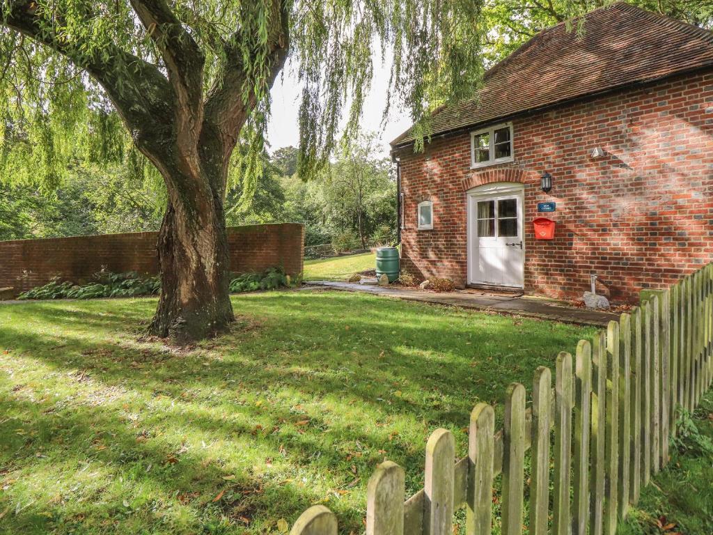 a brick house with a fence and a tree at Weir Cottage in Maidstone