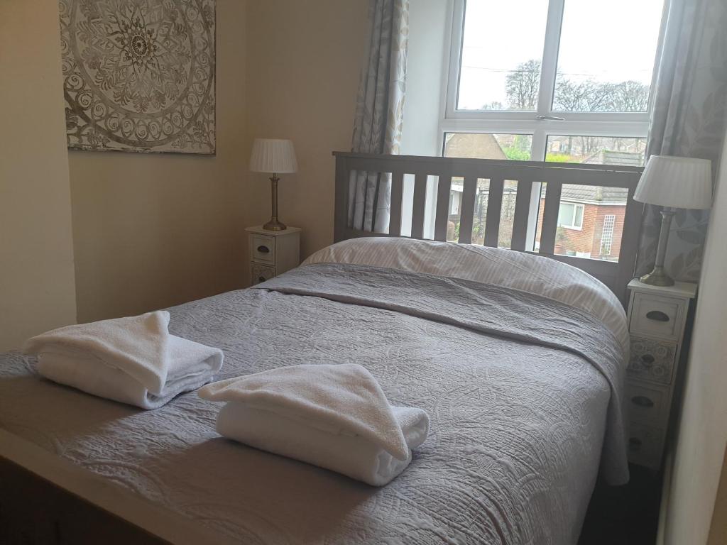a bedroom with two towels on a bed with a window at BlueBells at Plover Cottage Lindley in Huddersfield