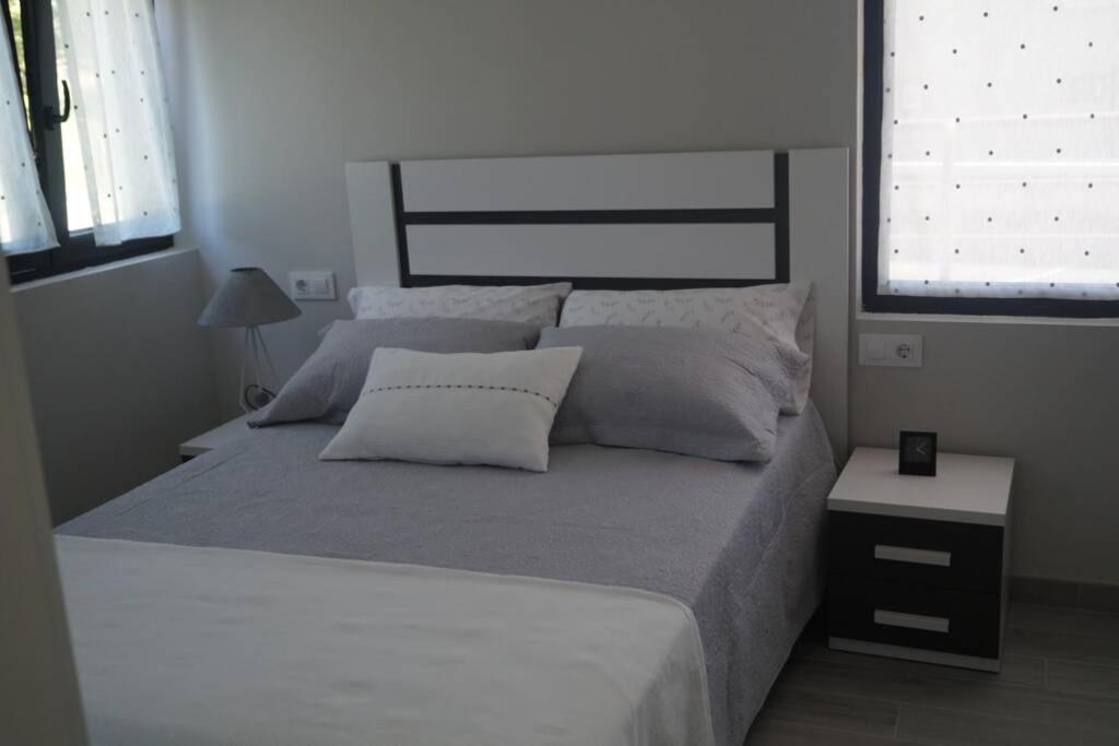 um quarto com uma cama grande com lençóis brancos e almofadas em Apartamentos los Acantilados Nº 1 Cobreces em Cóbreces