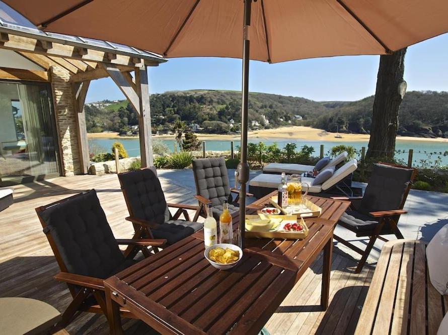 a wooden table with chairs and an umbrella on a deck at Woodwell in Salcombe
