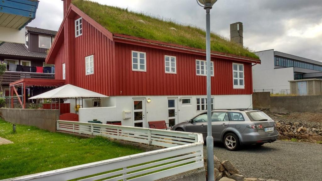 a car parked in front of a red house with a grass roof at Bed & Breakfast Torshavn in Tórshavn