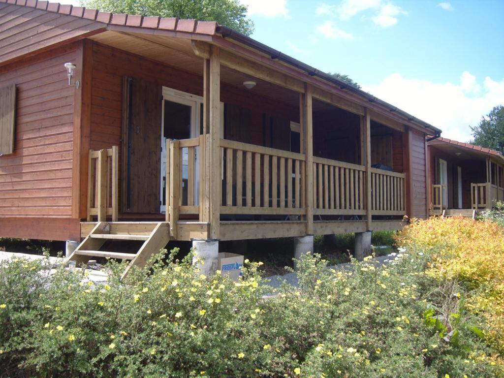 a large wooden cabin with a porch and a porch at Chalet 70, La butte aux cerfs in Campagnolles