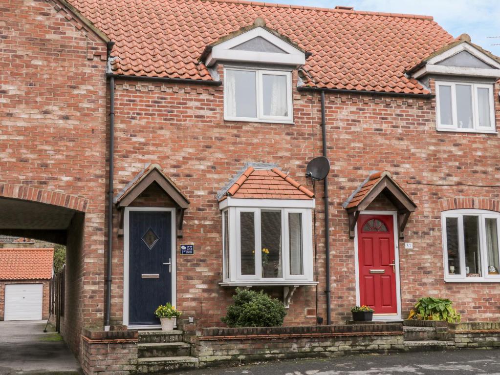a brick house with a red door and white windows at Little Daisy Cottage in Hornsea