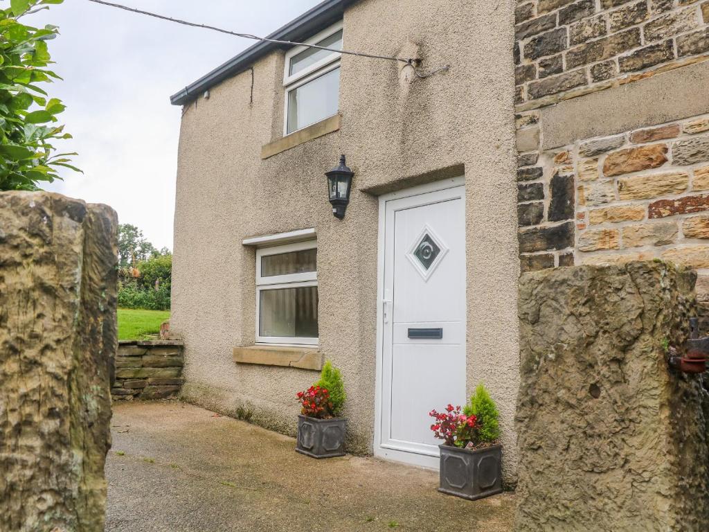 a brick house with a white door and two potted plants at Stone Farm Cottage in Sheffield