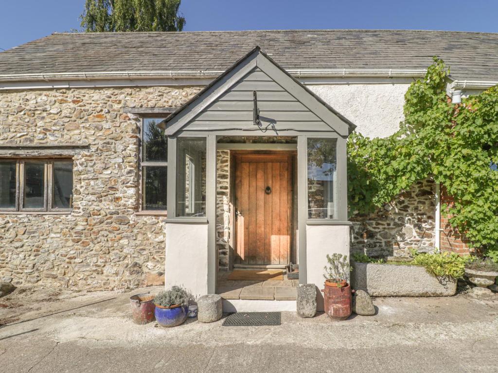 una casa de piedra con una puerta de madera delante de ella en The Barn en Honiton