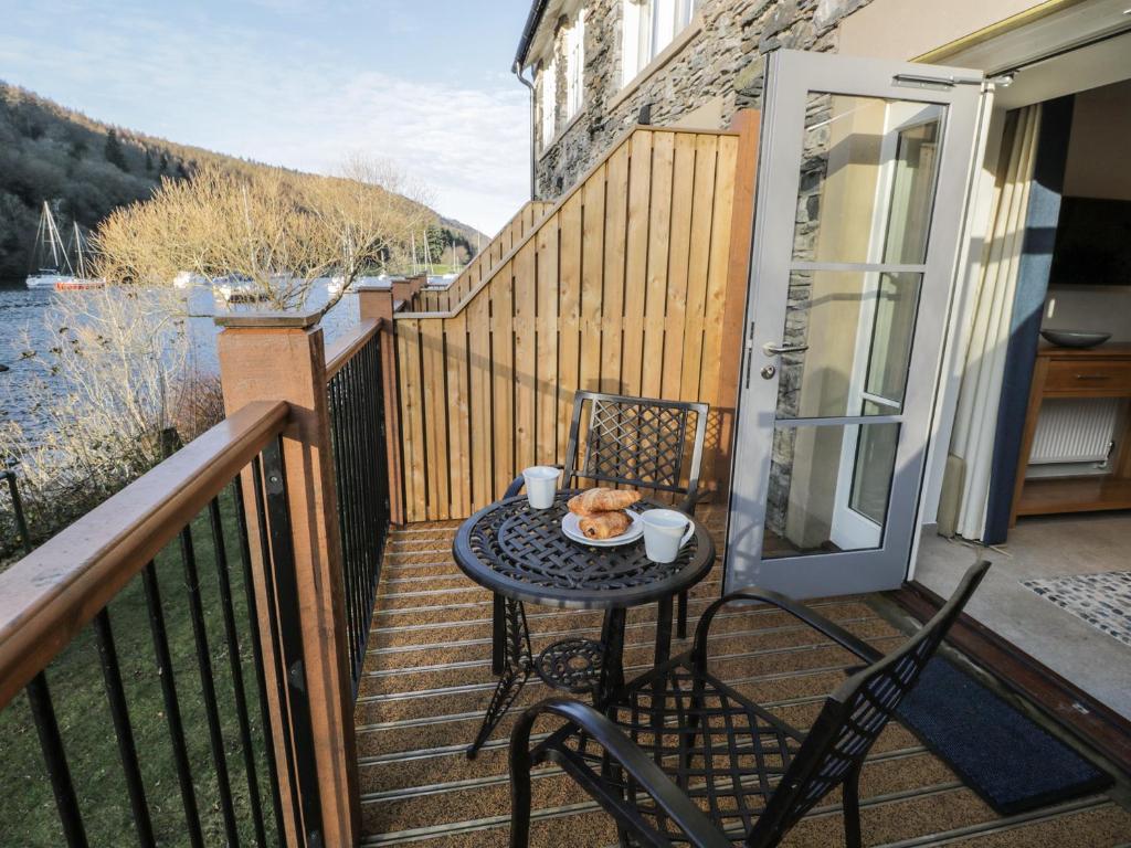 a table and chairs on a balcony with a view of the water at Pennington in Ambleside