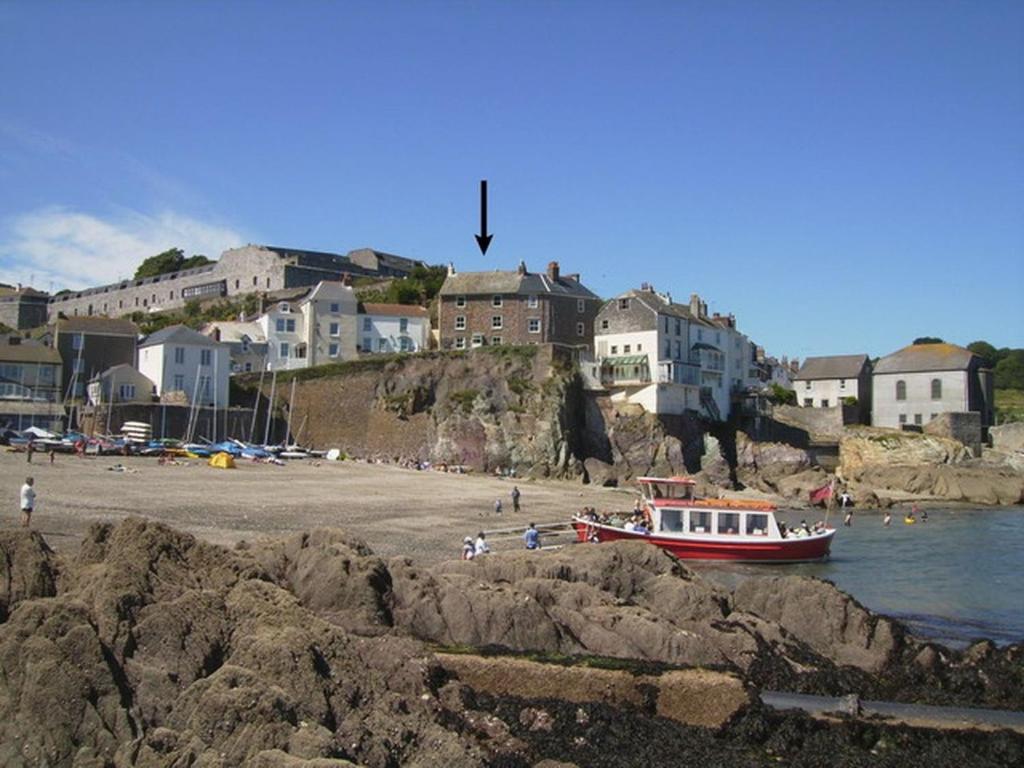 a boat on a beach with houses in the background at Balcony Cottage in Cawsand