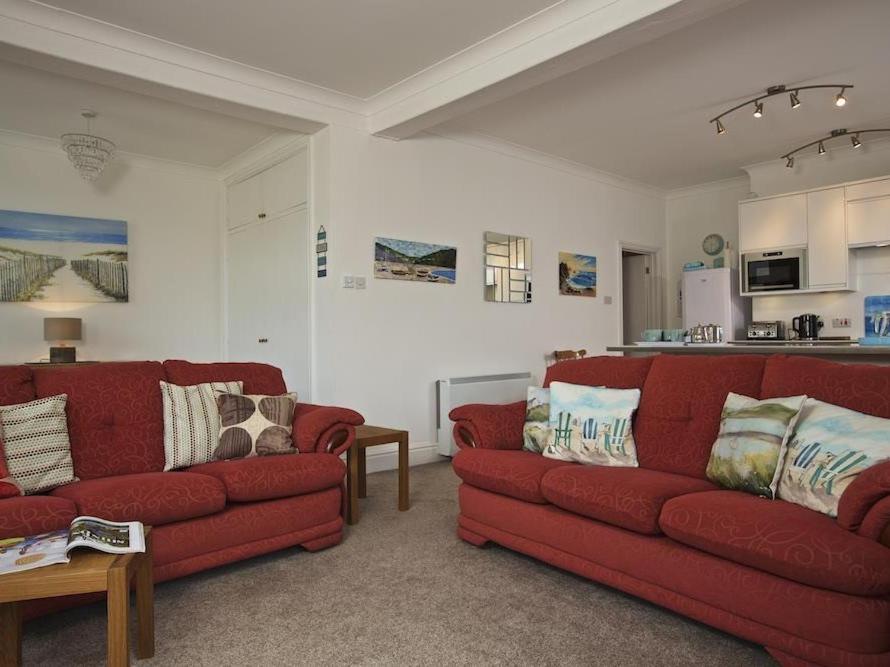a living room with two red couches and a kitchen at Cove View in Kingsbridge