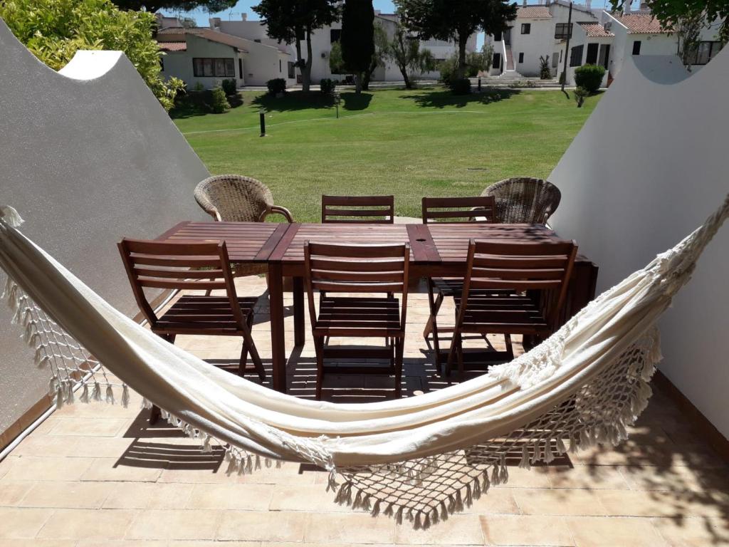 een hangmat op een patio met een tafel en stoelen bij Villa Pedras d'el Rei in Santa Luzia