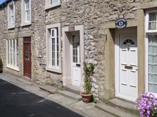 a stone building with white doors on a street at Bridle Cottage in Settle