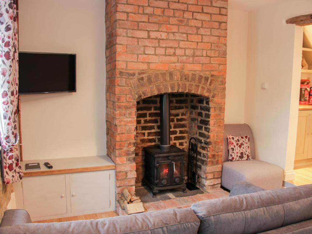 a brick fireplace with a stove in a living room at Pinner's Cottage in Knighton