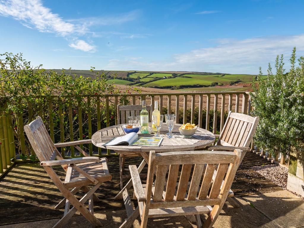 a wooden table with two chairs and a table with glasses at 164 Cumber Close in Kingsbridge